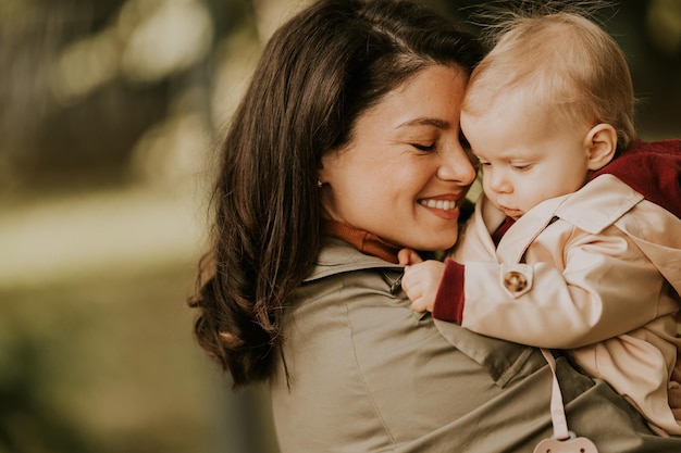 Foto giovane donna che tiene in braccio una carina bambina nel parco d'autunno