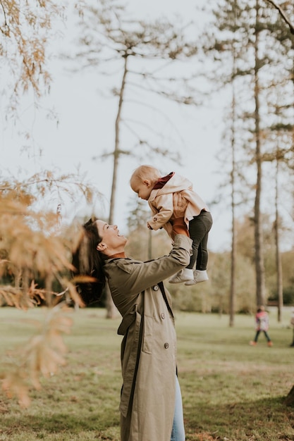 Young woman holding a cute baby girl in the autumn park