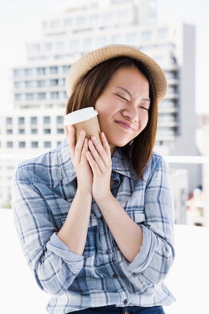 Young woman holding disposable cup outdoors