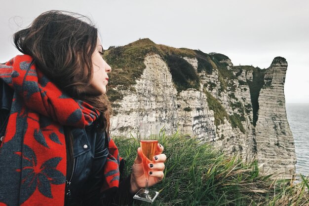 Foto giovane donna con un drink contro la scogliera