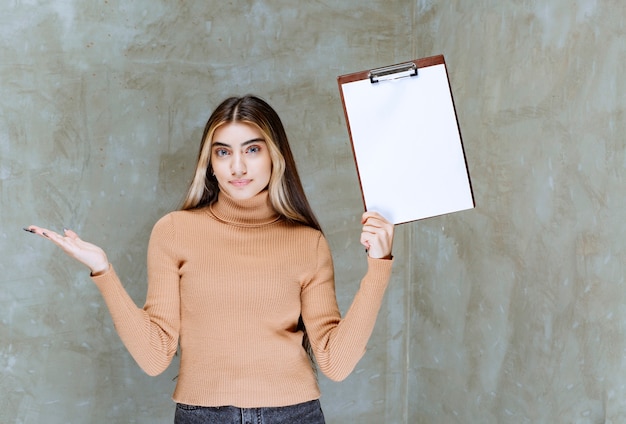 Young woman holding an empty notepad on a stone 