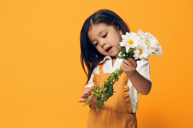 Young woman holding flowers against yellow background