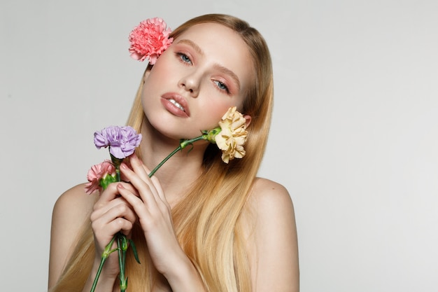 Young woman holding flowers and posing in a studio