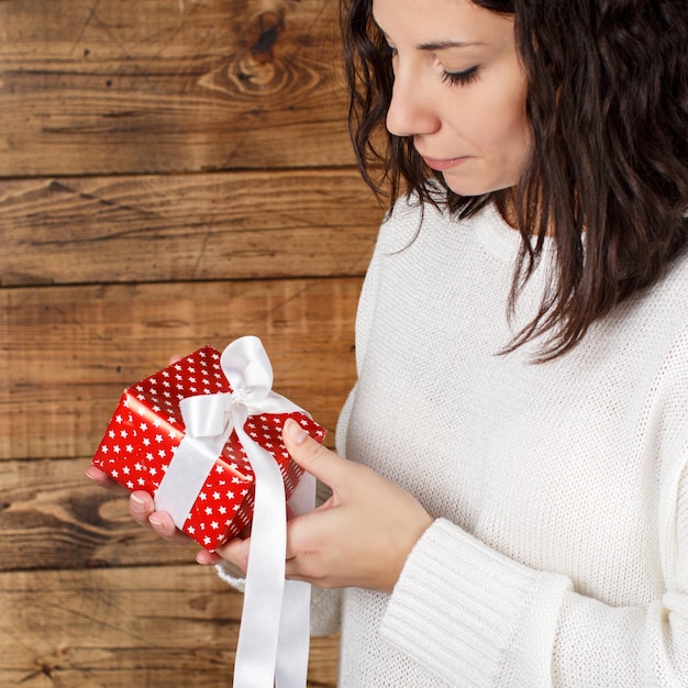 Foto giovane donna con un pacchetto regalo in mano vicino sullo sfondo di legno