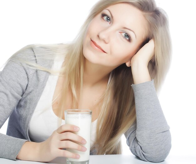新鮮なミルクのガラスを保持している若い女性