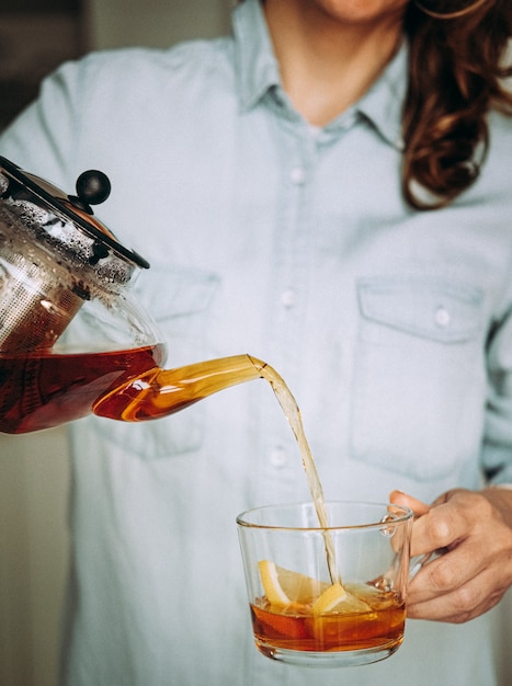 Young woman holding a glass teapot. Woman pouring tea