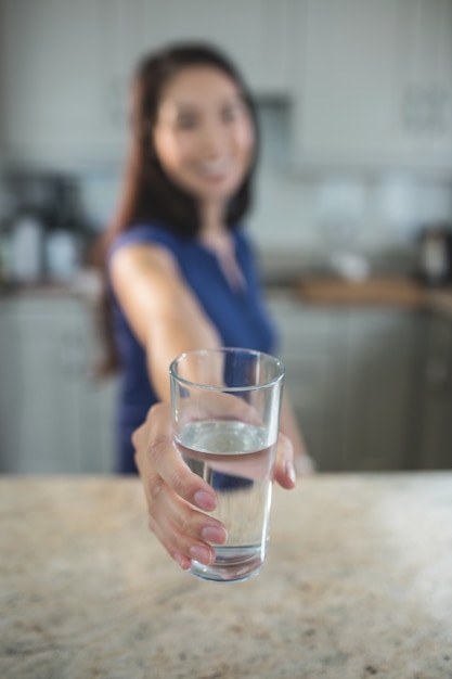 Foto giovane donna che tiene un bicchiere d'acqua in cucina