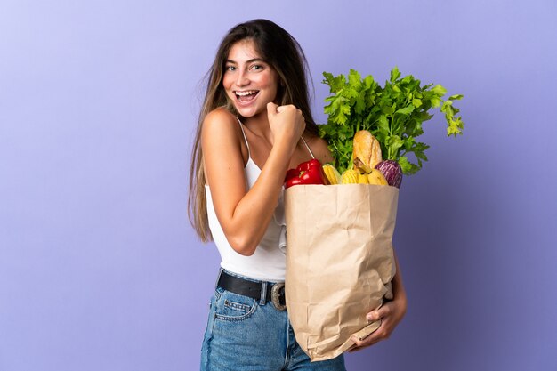 食料品の買い物袋を保持している若い女性