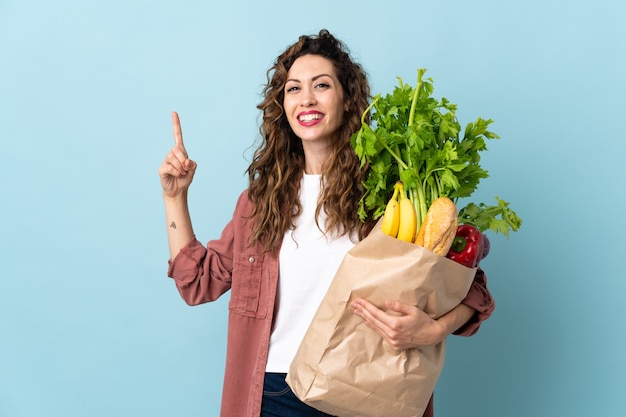 食料品の買い物袋を持っている若い女性