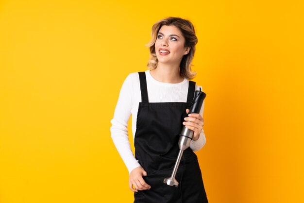 Young woman holding a hand blender