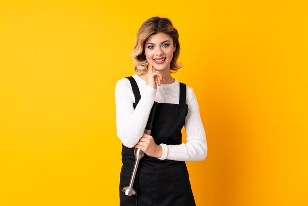 Young woman holding a hand blender