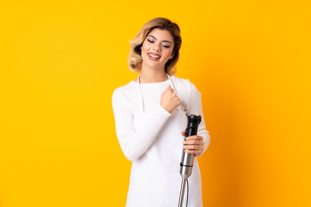 Young woman holding a hand blender