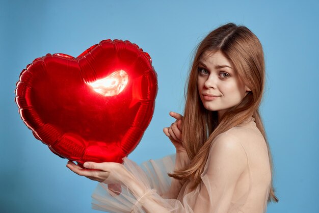 Young woman holding heart shape against blue background
