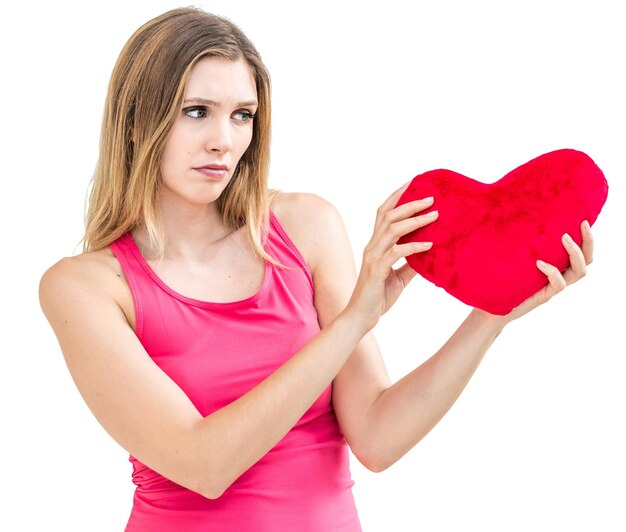 Photo young woman holding heart shape while standing against white background