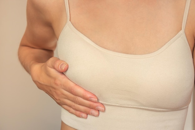Фото Молодая женщина, держащая груди рукой. самоанализ груди. женское здоровье и маммология.