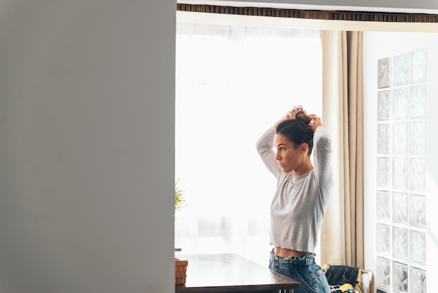 Foto giovane donna che tiene i capelli in una stanza