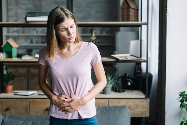 Photo young woman holding her stomach in pain