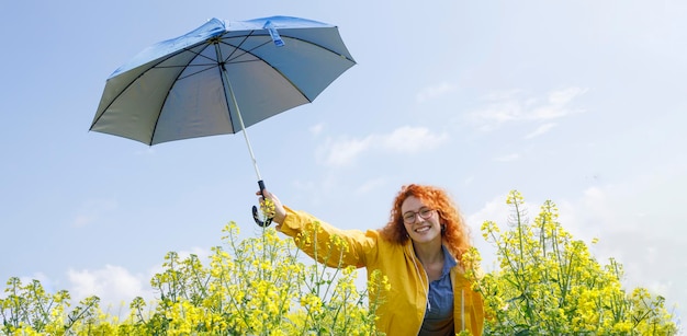 Молодая женщина держит зонтик и улыбается в летний день сразу после дождя