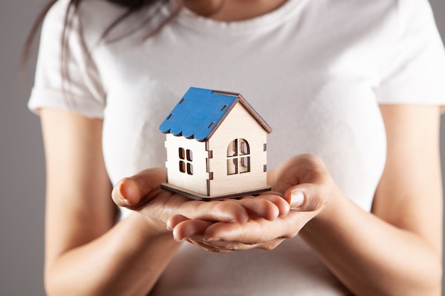 Young woman holding house in hands