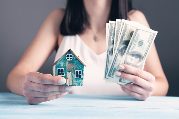 Young woman holding house and money