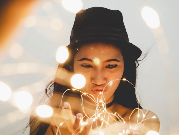 Photo young woman holding illuminated string lights