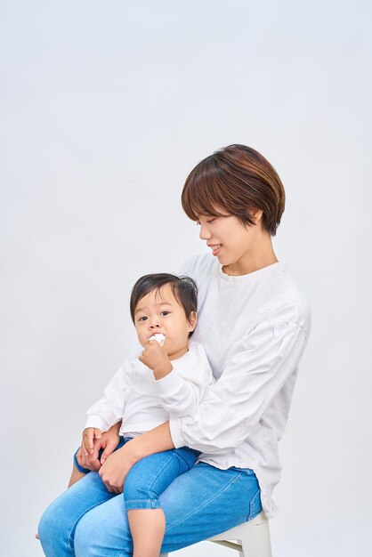 young woman holding an infant and white background