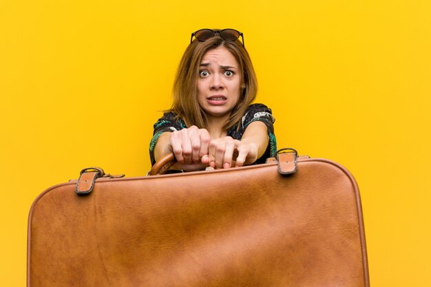 Young woman holding a leather bag  scared about her vacations, she has fobia to fly.