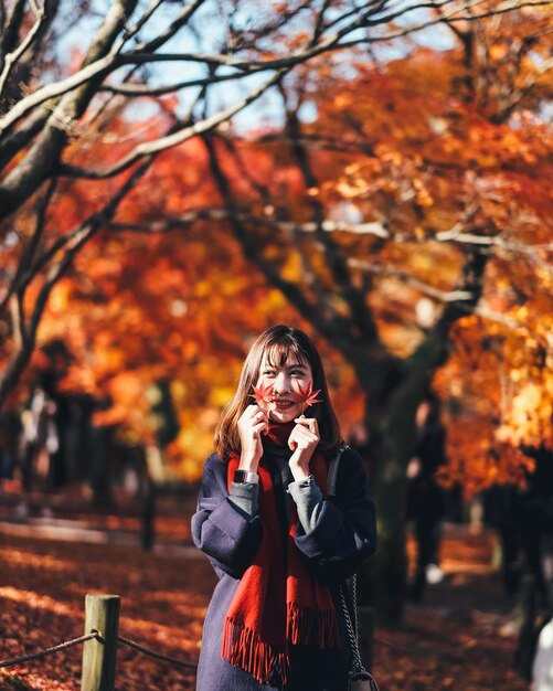 Photo young woman holding leaves during autumn