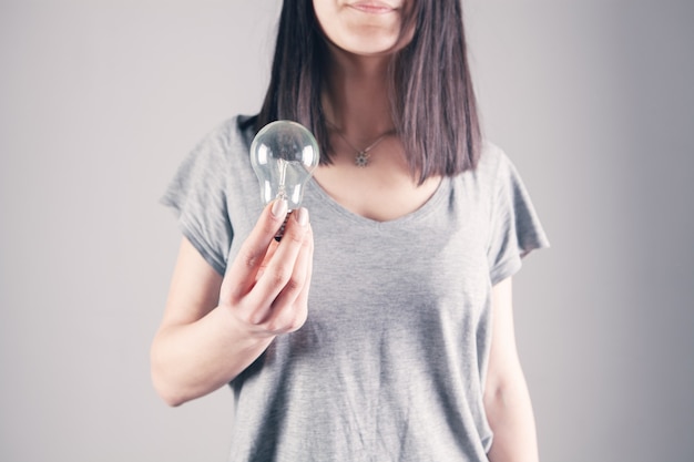 Giovane donna con in mano una lampadina