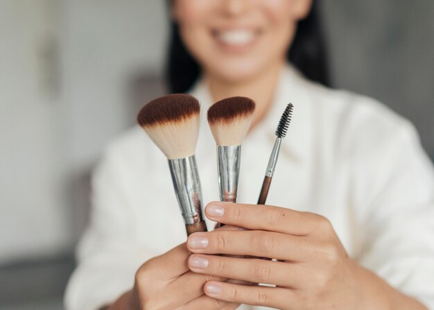 Photo young woman holding make up brushes