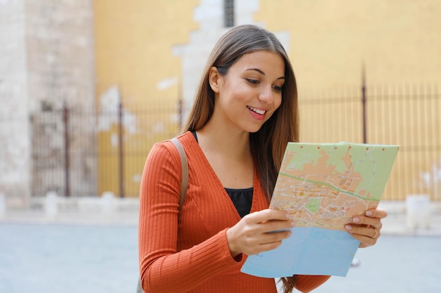 Foto giovane donna con una mappa in piedi in città