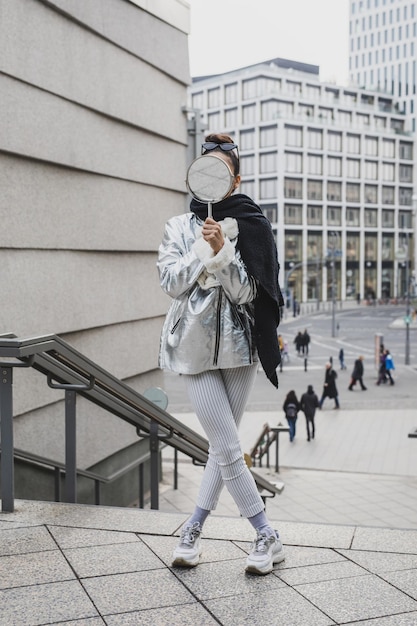 Photo young woman holding mirror while standing on steps in city