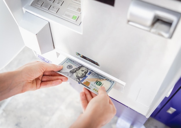 Young woman holding money in her hands after withdrawing the cash at the atm