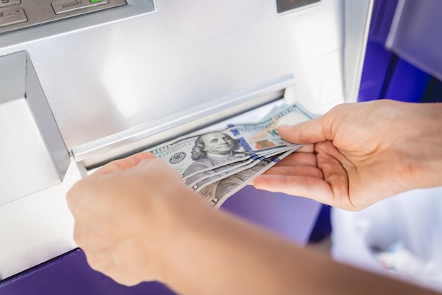 Young woman holding money in her hands after withdrawing the cash at the atm