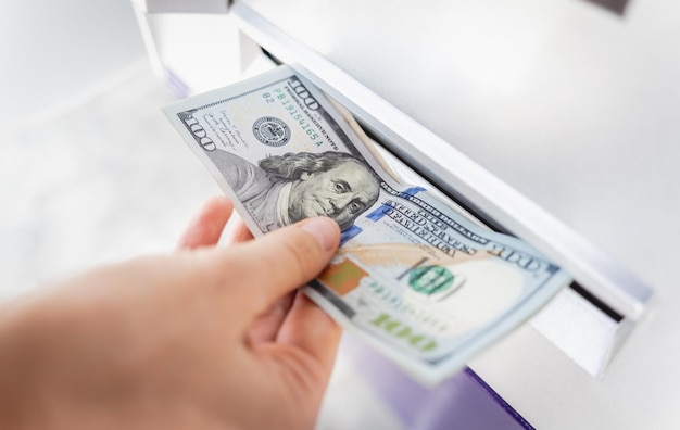 Young woman holding money in her hands after withdrawing the cash at the atm