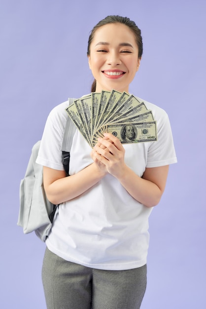 Young woman holding money isolated on purple background