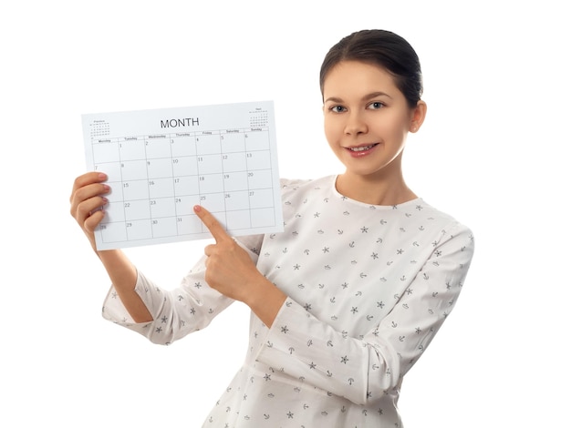 Young woman holding monthly calendar and pointing the date on white background