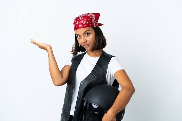 Young woman holding a motorcycle helmet isolated on white extending hands to the side for inviting to come