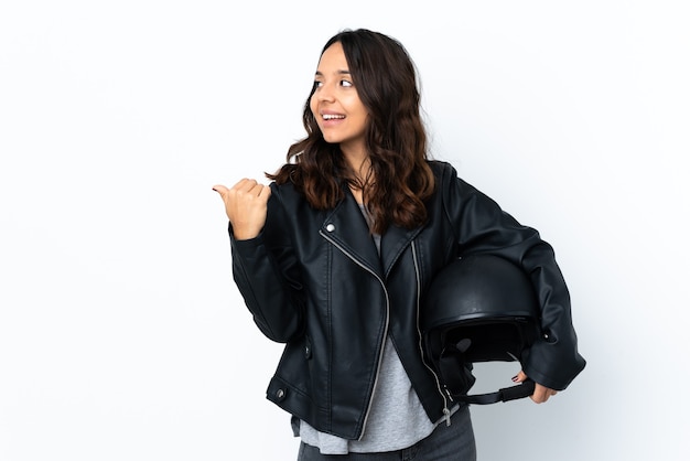 제품을 제시하는 측면을 가리키는 격리 된 흰색 위에 오토바이 헬멧을 들고 젊은 여자