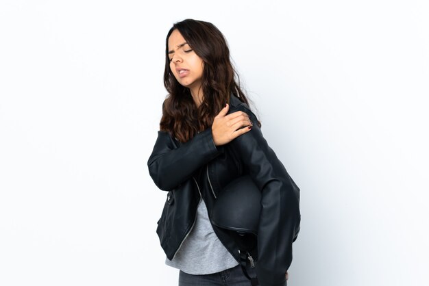 Young woman holding a motorcycle helmet over isolated white wall suffering from pain in shoulder for having made an effort