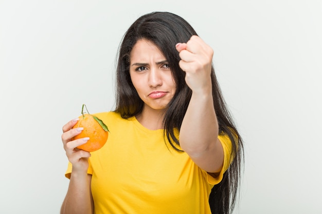 Young  woman holding an orange showing fist