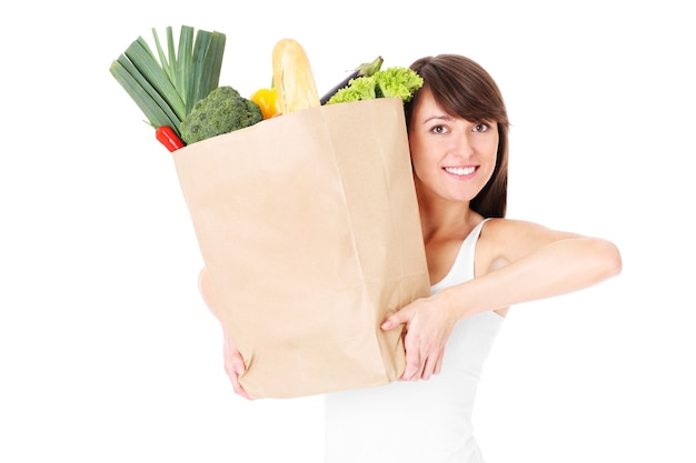 a young woman holding a paper bag full of vegetables over white background