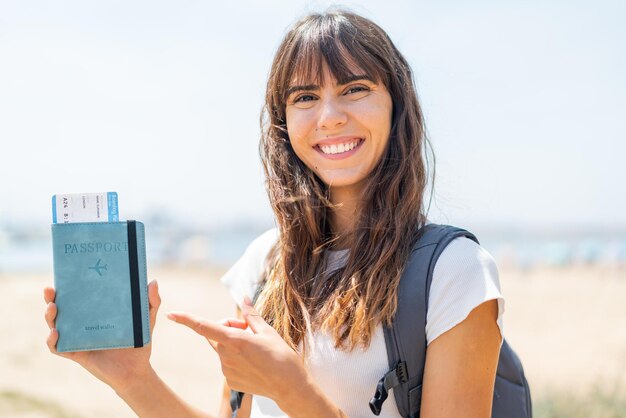 Young woman holding a passport at outdoors and pointing it