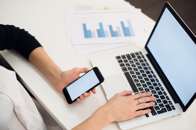 Photo young woman holding a phone and using laptop