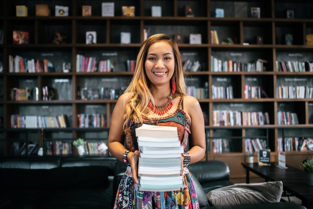 Libri del mucchio della tenuta della giovane donna in una caffetteria