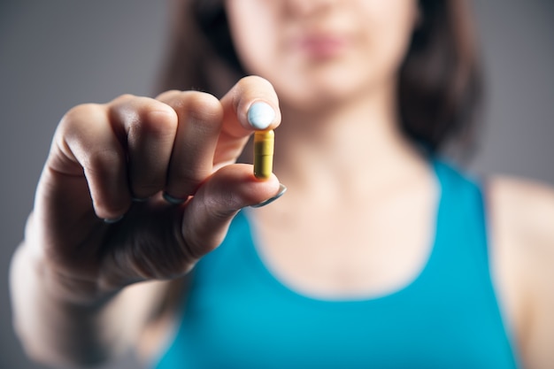 Young woman holding a pill