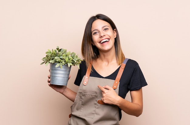 Young woman holding a plant with surprise facial expression