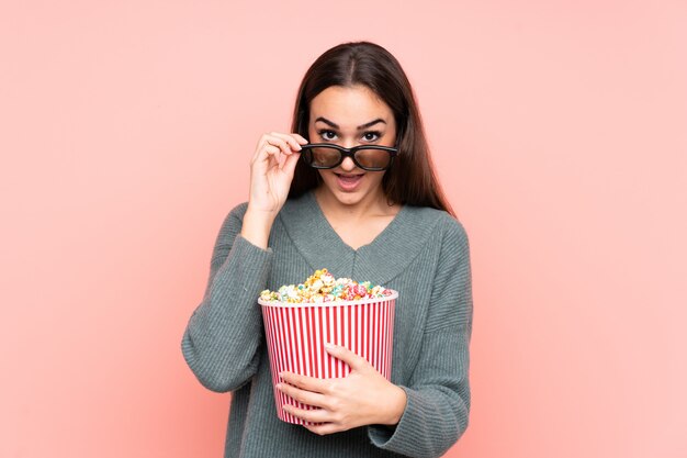 Young woman holding popcorns over isolated wall