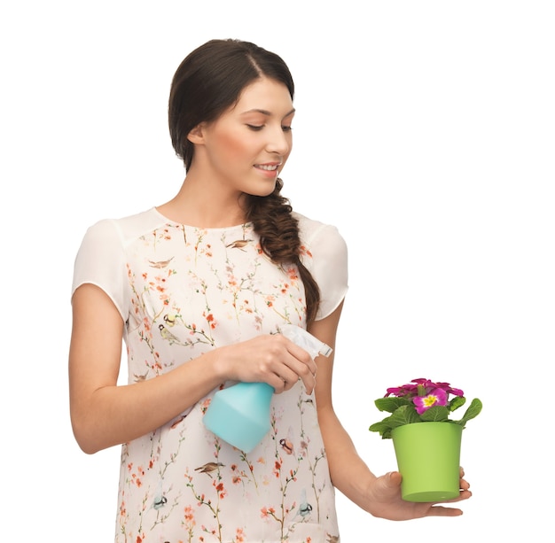 young woman holding pot with flower and spray bottle