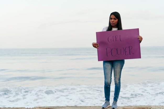 Young woman holding a protest message on purple.